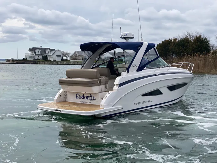  Yacht Photos Pics 2015 Regal 32 Express boat cruising on a calm waterway near a coastal house.