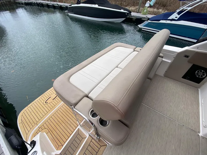  Yacht Photos Pics 2015 Regal 32 Express boat with beige seating and wooden deck by the water.