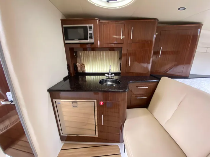  Yacht Photos Pics Compact kitchen area in a 2015 Regal 32 Express boat with wood cabinetry and modern appliances.