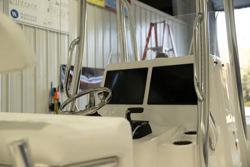  Yacht Photos Pics 2025 Contender 26 Bay boat interior with dual screens and steering wheel in a workshop.
