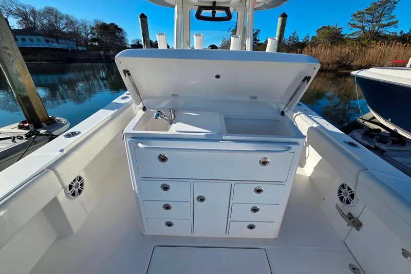 Three Ladies Yacht Photos Pics 2021 Regulator 34 boat with open storage compartment and sink, docked by calm waters.