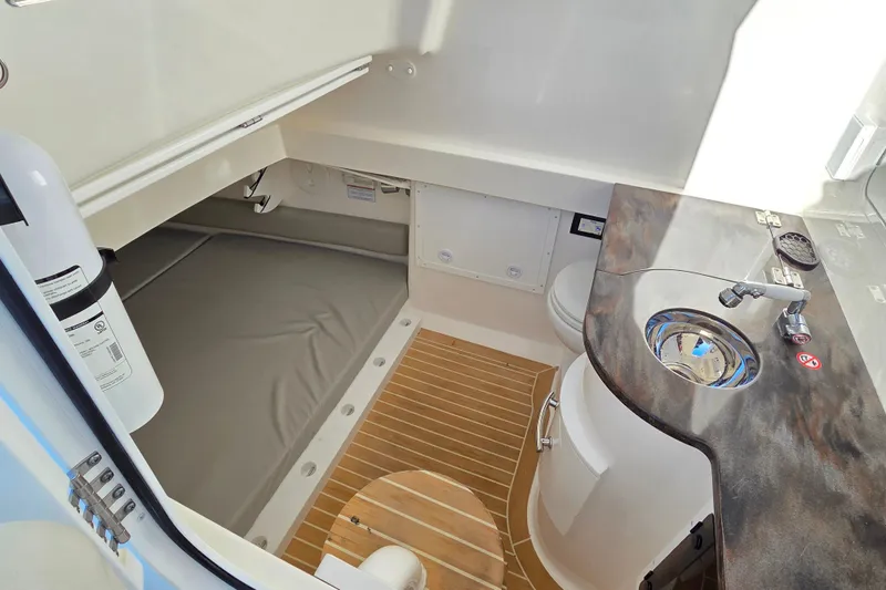 Three Ladies Yacht Photos Pics 2021 Regulator 34 boat interior with sink, toilet, and cushioned bench.