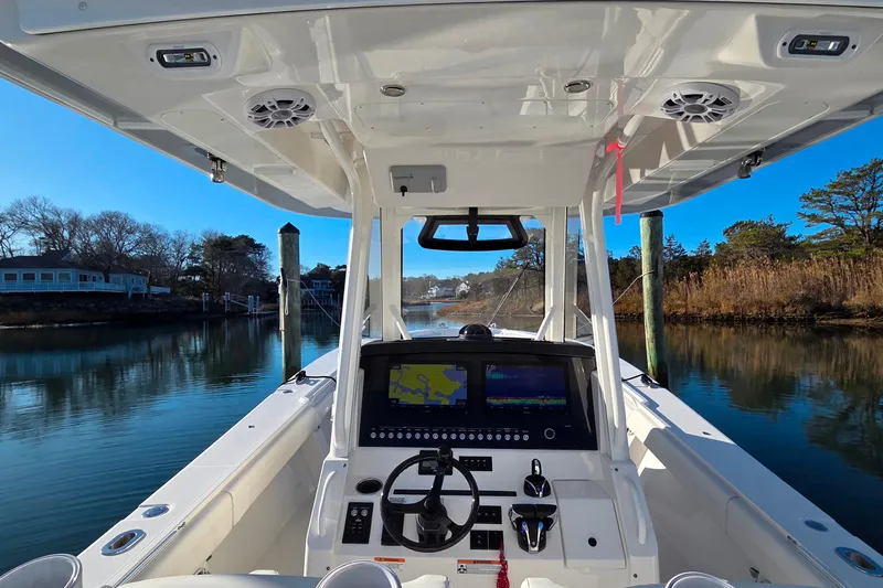 Three Ladies Yacht Photos Pics 2021 Regulator 34 boat cockpit with navigation screens, steering wheel, and serene waterway view.