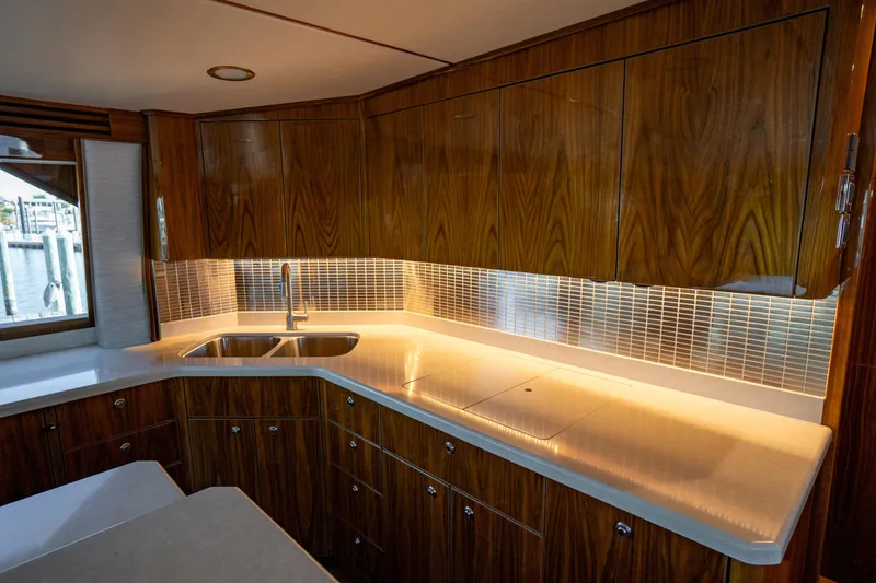 Galati Yacht Sales Trade Yacht Photos Pics Luxurious kitchen interior of 2021 Viking 72 Enclosed Bridge yacht with wood cabinetry and modern fixtures.