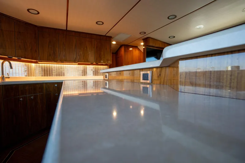 Galati Yacht Sales Trade Yacht Photos Pics Luxurious interior of 2021 Viking 72 Enclosed Bridge yacht with sleek countertops and wood cabinetry.