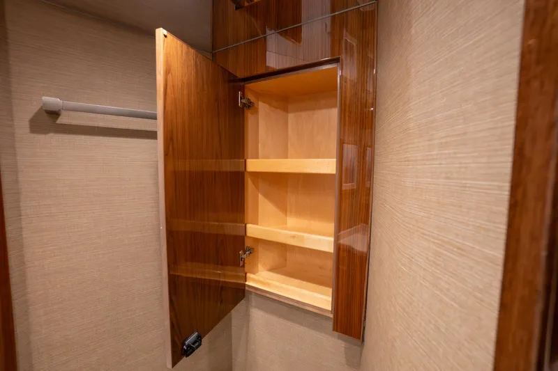 Galati Yacht Sales Trade Yacht Photos Pics Open wooden cabinet with shelves inside a 2021 Viking 72 Enclosed Bridge yacht.