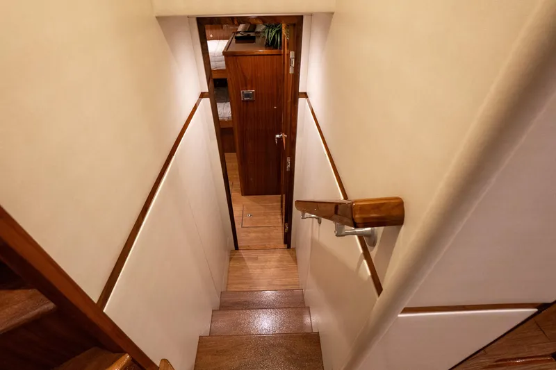 Galati Yacht Sales Trade Yacht Photos Pics Stairway inside 2021 Viking 72 Enclosed Bridge yacht, featuring wooden steps and handrail.