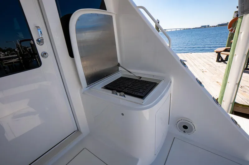 Galati Yacht Sales Trade Yacht Photos Pics Outdoor grill on 2021 Viking 72 Enclosed Bridge yacht, docked by the water.