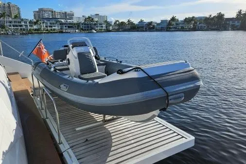 Sunlove Yacht Photos Pics 2024 Lagoon SIXTY 7 yacht with a small boat on the deck, docked by waterfront homes.