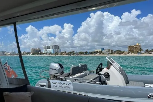 Sunlove Yacht Photos Pics 2024 Lagoon SIXTY 7 yacht with Highfield tender, coastal view, clear skies, and turquoise waters.