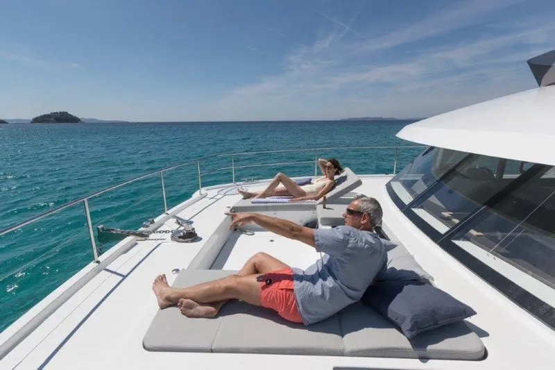  Yacht Photos Pics Couple relaxing on 2025 Fountaine Pajot MY6 yacht, enjoying sunny ocean views.