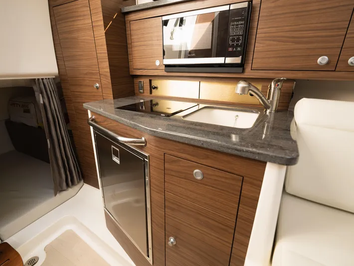  Yacht Photos Pics 2020 Boston Whaler 325 Conquest Pilothouse kitchen with modern appliances and wood cabinetry.
