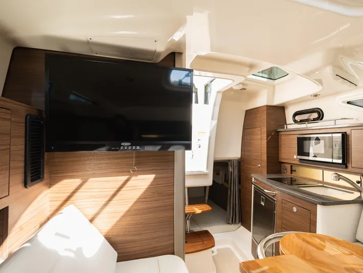  Yacht Photos Pics Interior of 2020 Boston Whaler 325 Conquest Pilothouse with TV, kitchenette, and seating area.