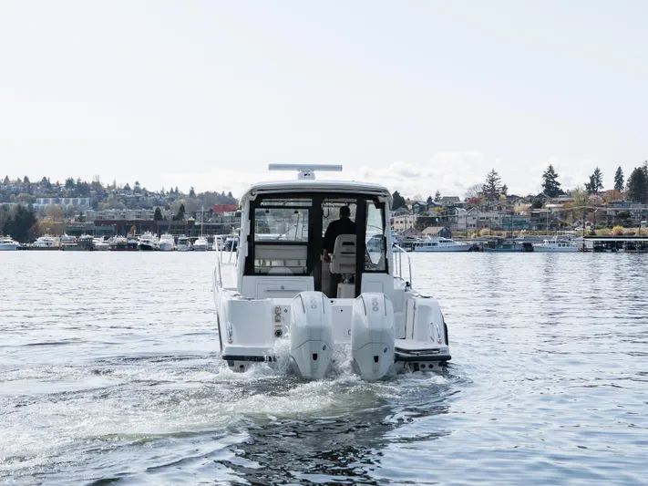  Yacht Photos Pics Boston Whaler 325 Conquest Pilothouse 2020 cruising on a calm lake near a town.