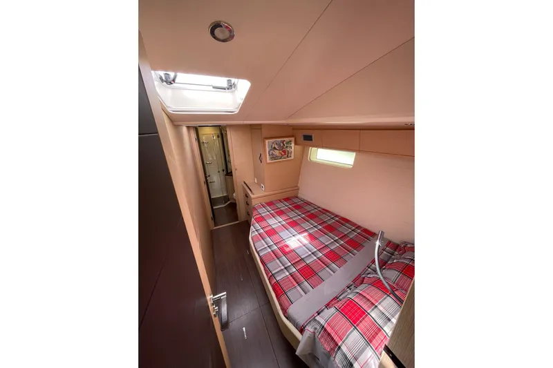  Yacht Photos Pics Luxurious cabin interior of 2017 Jeanneau 64 yacht with plaid bedding and skylight.