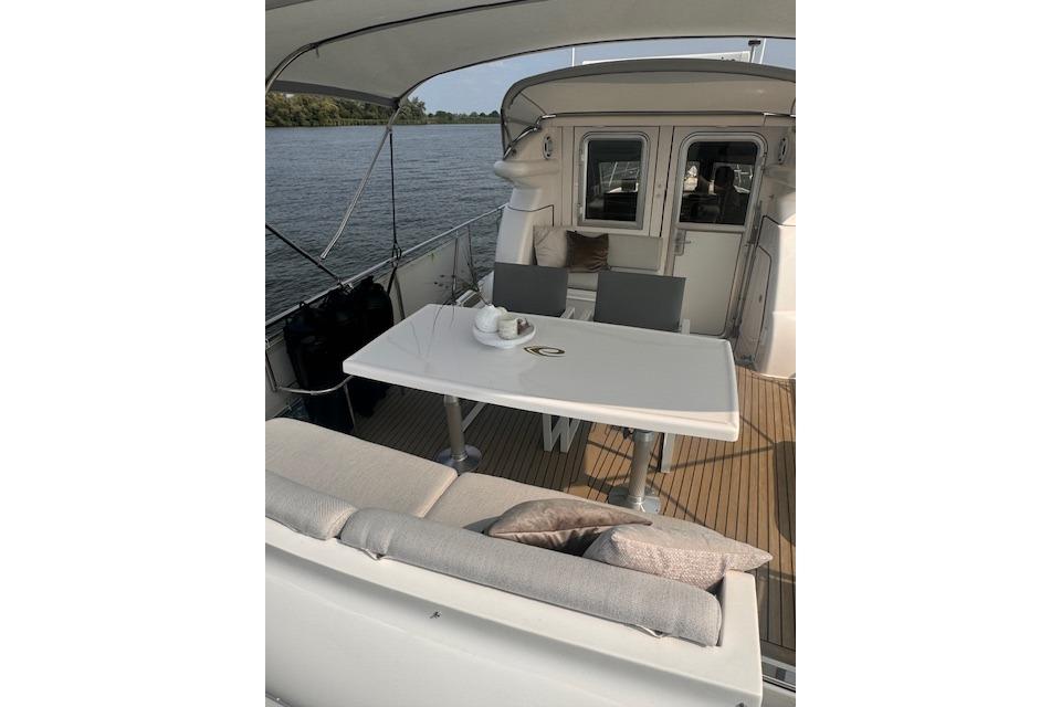 2017 Elling E4 yacht deck with table, chairs, and cushions on a serene water backdrop.