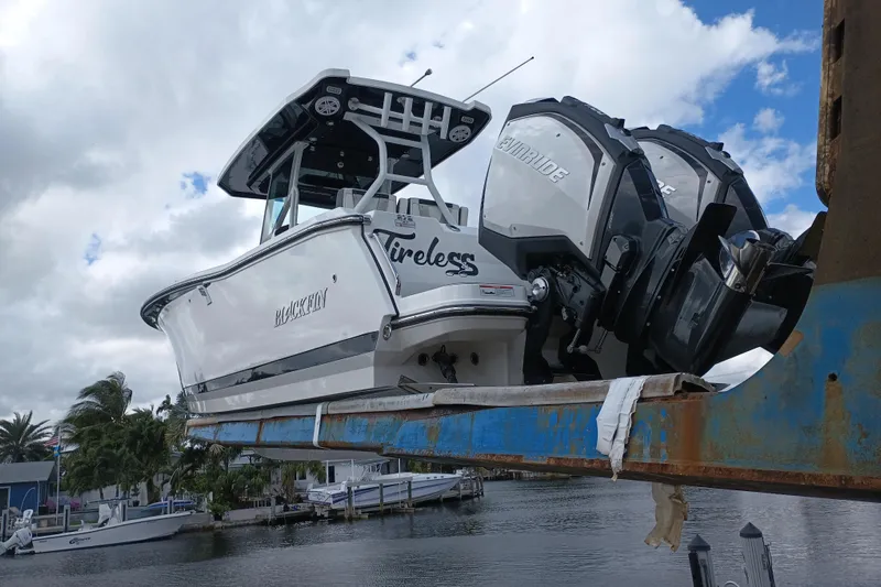  Yacht Photos Pics 2020 Blackfin 272 CC boat with dual Evinrude engines on a lift, cloudy sky background.