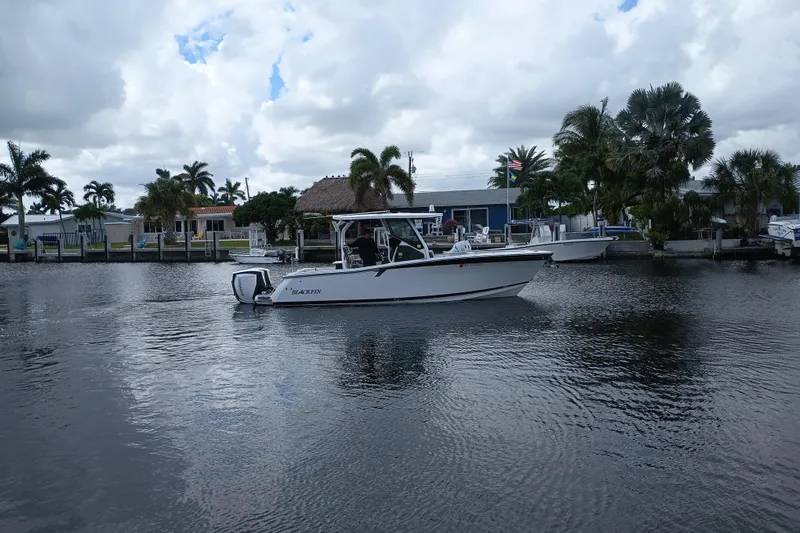  Yacht Photos Pics 2020 Blackfin 272 CC boat on a calm waterway with palm trees in the background.