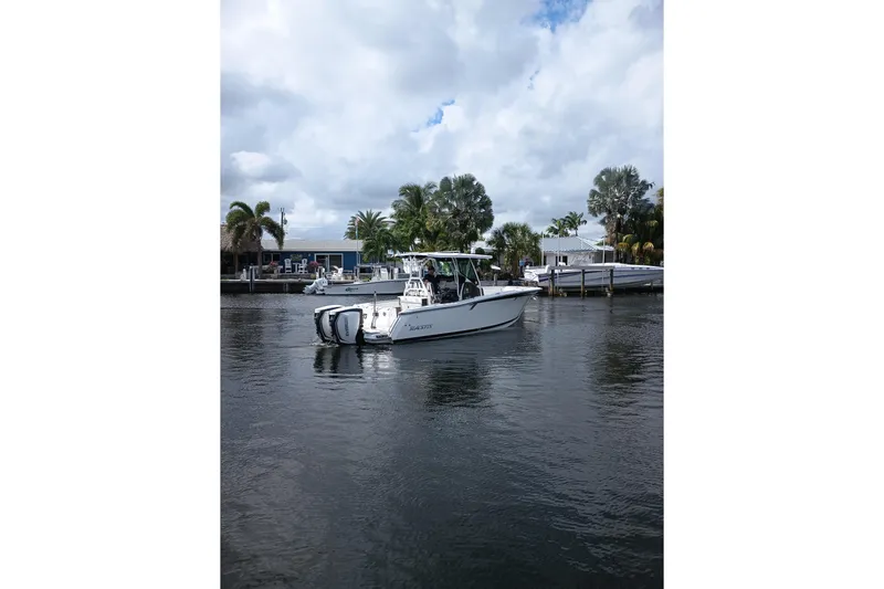  Yacht Photos Pics 2020 Blackfin 272 CC boat on calm water near a dock with palm trees.