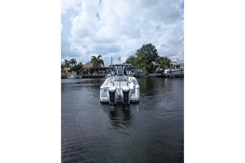  Yacht Photos Pics 2020 Blackfin 272 CC boat on water, surrounded by palm trees and cloudy sky.
