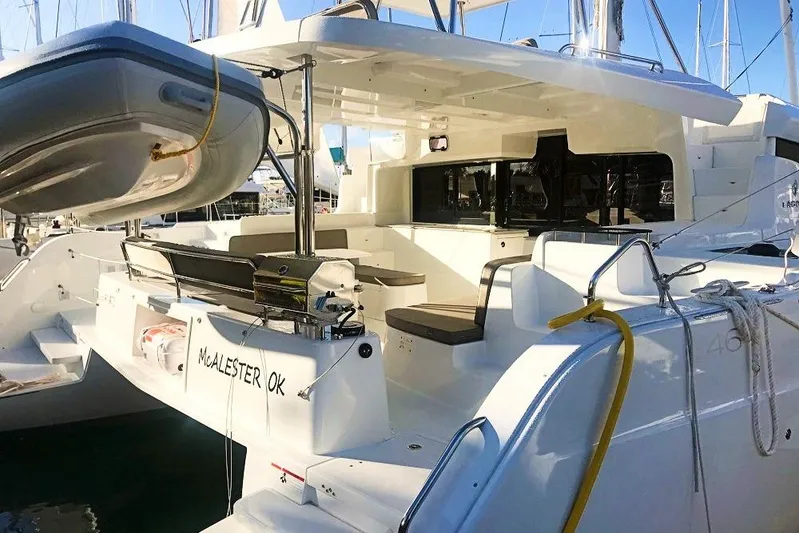 Spanky's Gang Yacht Photos Pics 2021 Lagoon 46 catamaran with spacious deck and dinghy, docked in a marina.