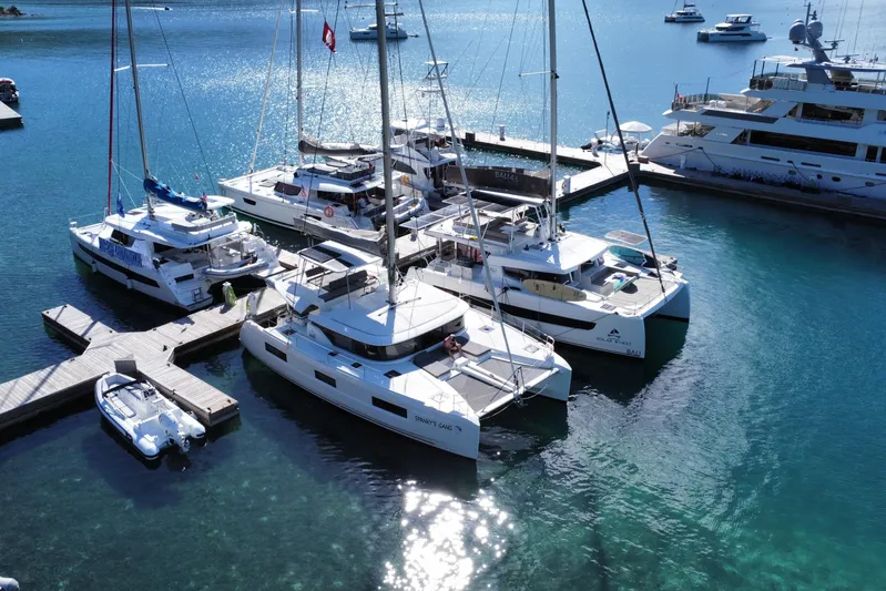 Spanky's Gang Yacht Photos Pics 2021 Lagoon 46 catamaran docked among other boats in a sunny marina.