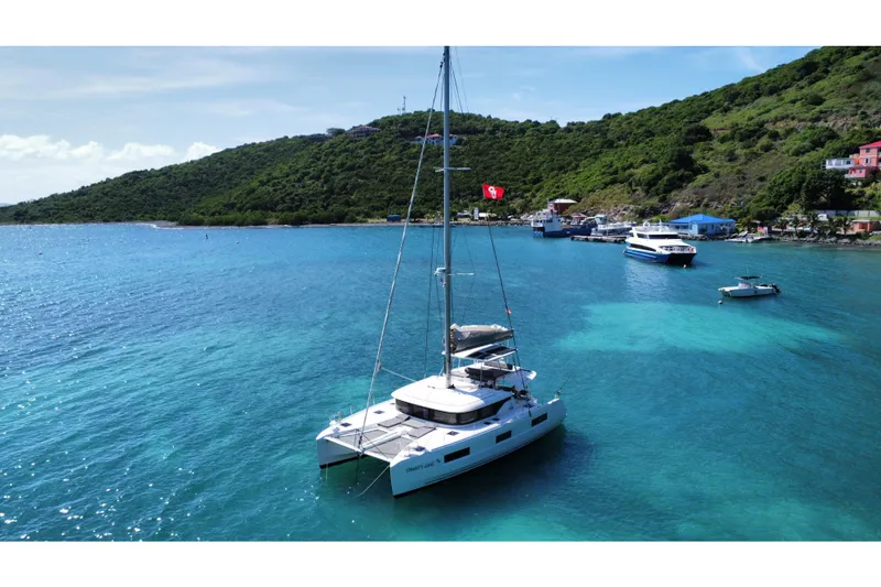 Spanky's Gang Yacht Photos Pics 2021 Lagoon 46 catamaran anchored in a scenic bay with lush green hills.