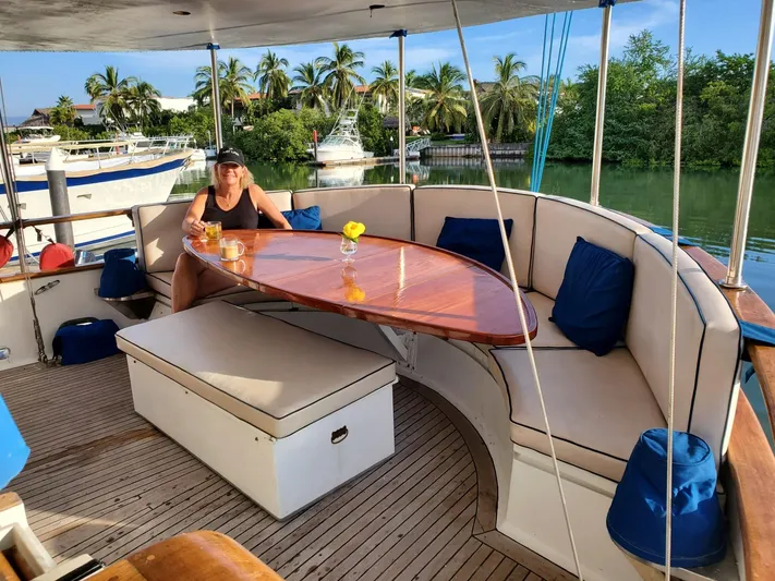  Yacht Photos Pics Woman relaxing on 1982 Cheoy Lee 52 yacht with outdoor seating and table.