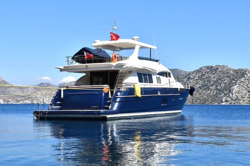  Yacht Photos Pics Luxury Princess 25M yacht from 2005 on serene blue waters, mountainous backdrop.