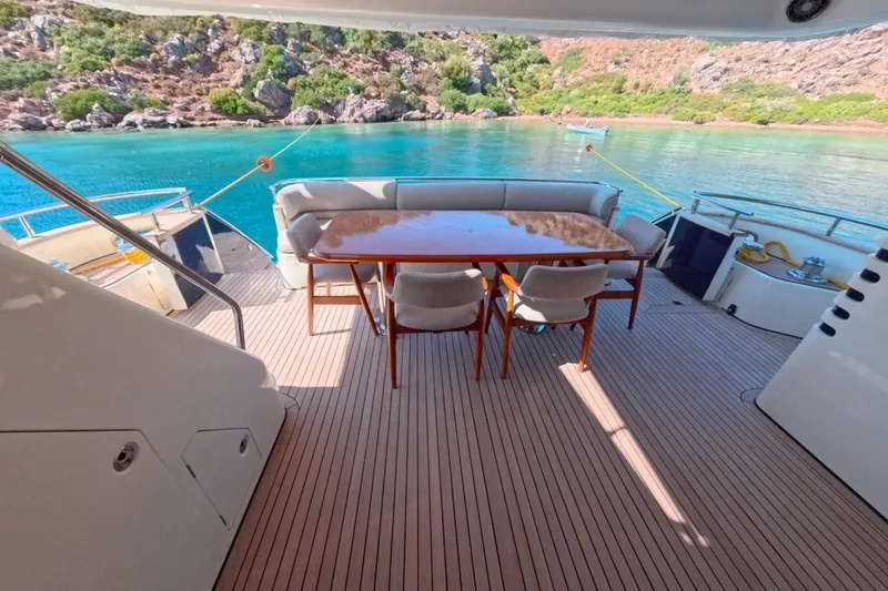  Yacht Photos Pics Luxury yacht deck with dining area, Princess 25M, 2005, overlooking turquoise waters and rocky shoreline.