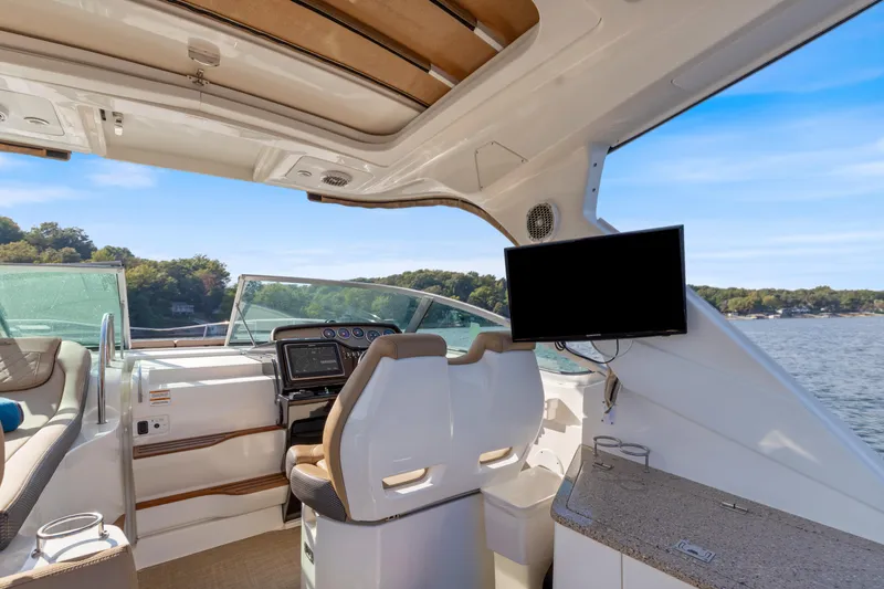  Yacht Photos Pics Interior of 2017 Sea Ray Sundancer 350 yacht with helm, seating, and TV, overlooking water.