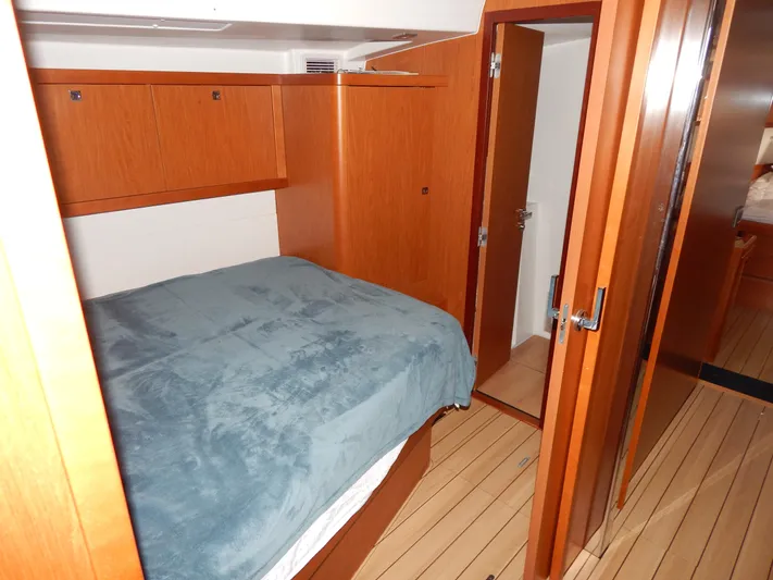  Yacht Photos Pics Cozy bedroom in 2015 Beneteau Sense 55 yacht with wooden interior and blue bedding.