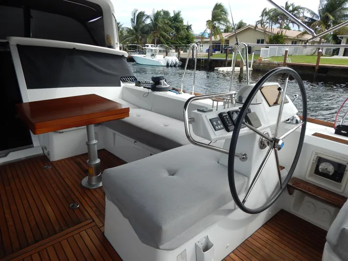  Yacht Photos Pics 2015 Beneteau Sense 55 yacht cockpit with steering wheel and seating, docked by palm trees.