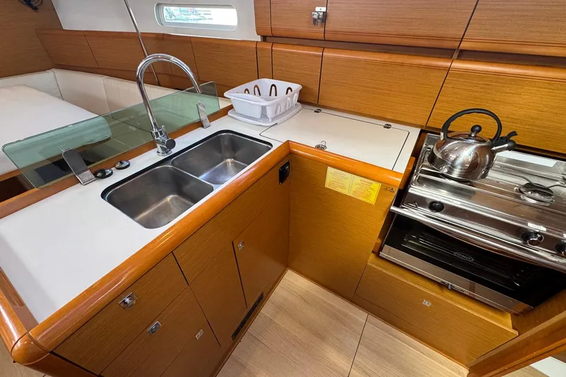 Sea Ranch II Yacht Photos Pics 2018 Jeanneau Sun Odyssey 389 yacht kitchen with sink, stove, and wooden cabinetry.