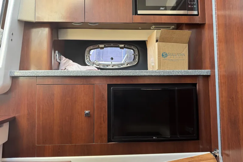  Yacht Photos Pics 2023 Chaparral 347 SSX interior with wood cabinetry, microwave, and small window.