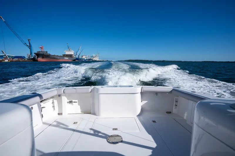 Reel Steel Yacht Photos Pics 2004 Cabo 35 Express boat cruising, leaving wake in harbor with ships and cranes.