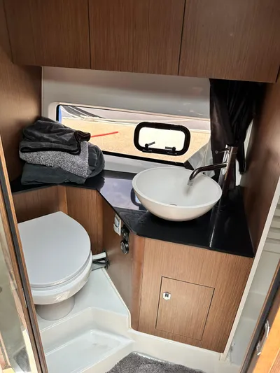 De-sea Yacht Photos Pics 2021 Beneteau GT 32 bathroom with modern sink, toilet, and wooden cabinetry.
