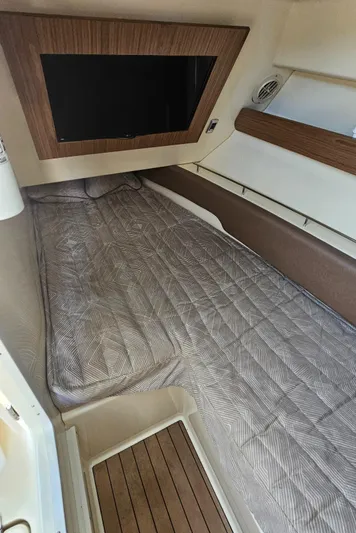  Yacht Photos Pics 2022 Chris-Craft Calypso 35 cabin interior with bed, wood accents, and wall-mounted TV.