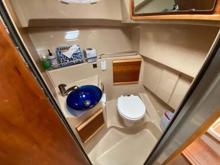  Yacht Photos Pics 2015 Cutwater C-28 boat bathroom with blue sink, toilet, and wooden accents.
