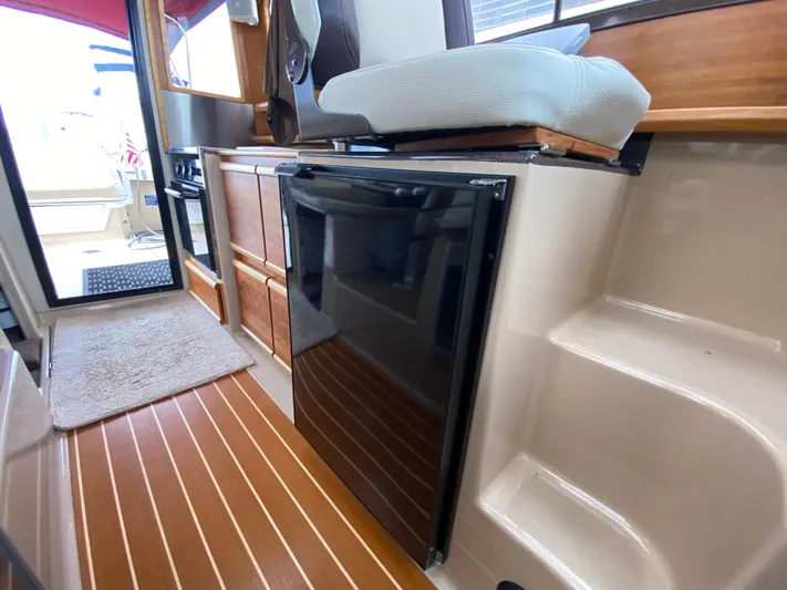  Yacht Photos Pics 2015 Cutwater C-28 interior with wood flooring, compact kitchen, and seating area.