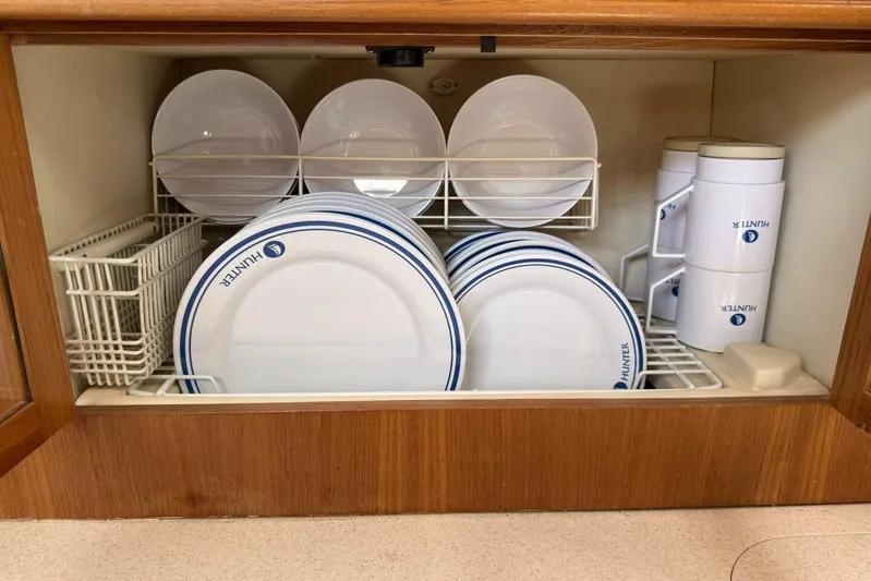  Yacht Photos Pics Hunter 46LE 2005 yacht kitchen with neatly organized plates and cups in a wooden cabinet.