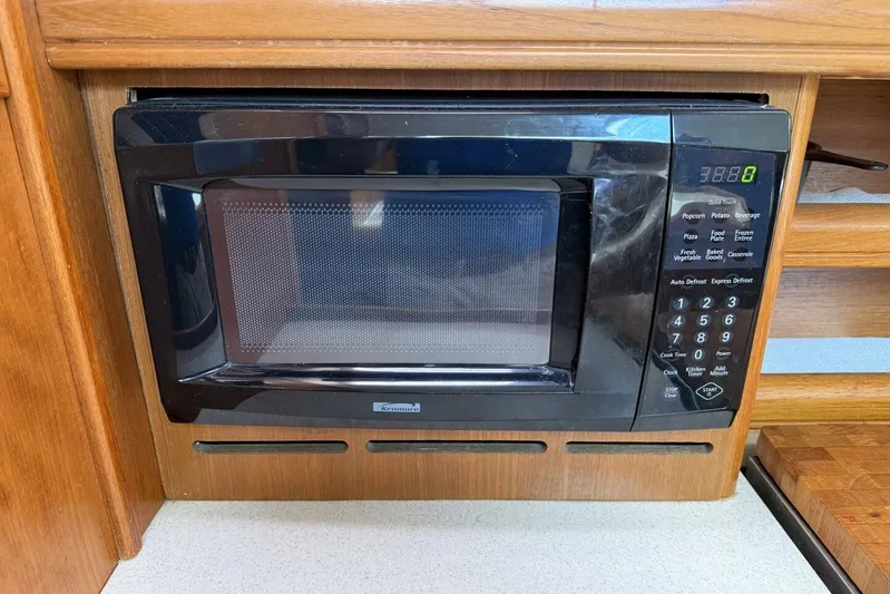  Yacht Photos Pics Built-in black microwave in wooden cabinetry, featuring digital display and control panel.