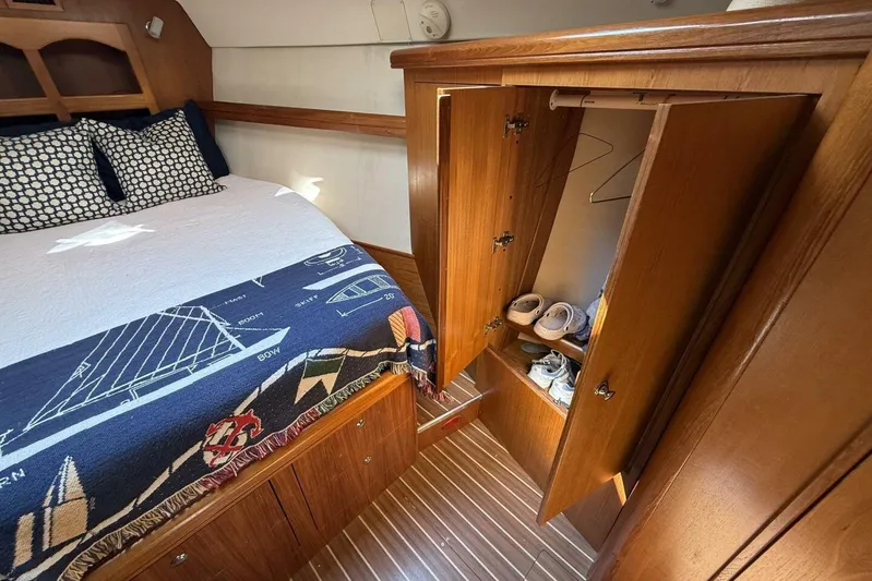 Yacht Photos Pics Cozy cabin interior of 2005 Hunter 46LE sailboat with bed and open wardrobe.