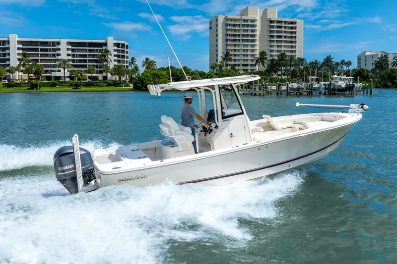  Yacht Photos Pics 2021 Regulator 26XO boat cruising on water near modern waterfront buildings.