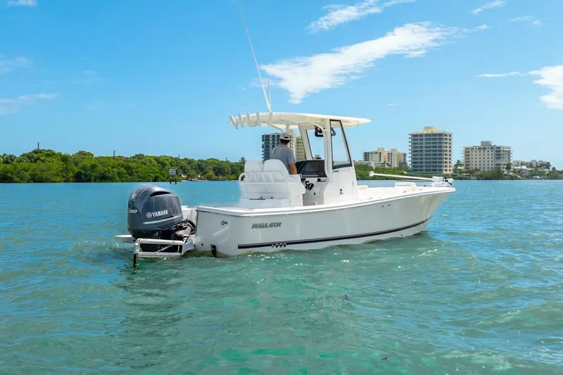 Yacht Photos Pics 2021 Regulator 26XO boat cruising on clear blue water near city skyline.