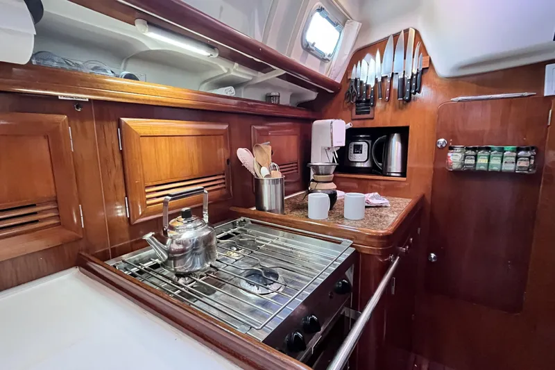 Windnsea Yacht Photos Pics Cozy kitchen in 2001 Beneteau 473 yacht with stove, kettle, and wooden cabinetry.