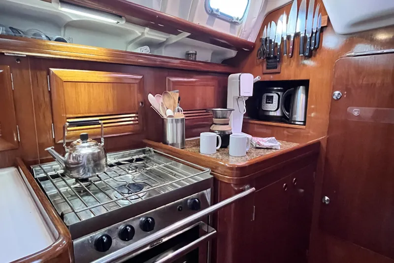Windnsea Yacht Photos Pics 2001 Beneteau 473 yacht kitchen with stove, kettle, and wooden cabinetry.