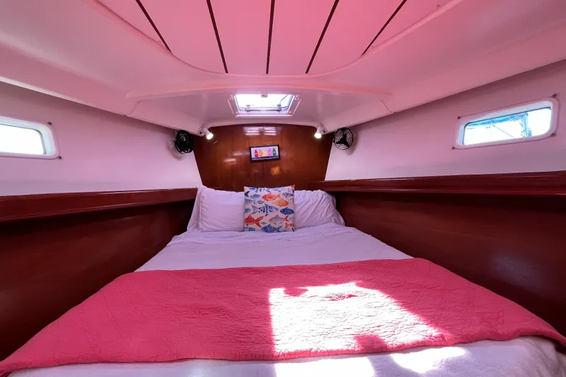 Windnsea Yacht Photos Pics Cozy cabin interior of 2001 Beneteau 473 sailboat with pink bedding and wooden accents.