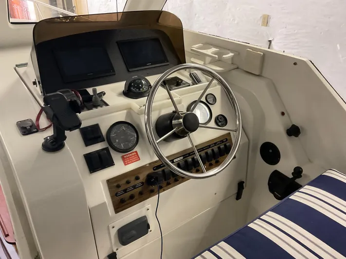  Yacht Photos Pics 2000 Mainship Pilot boat helm with steering wheel, gauges, and striped seating.
