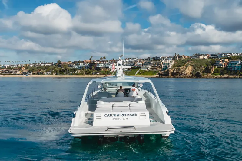 Catch & Release Yacht Photos Pics Custom 60 yacht cruising near coastal homes under a partly cloudy sky, 2017 model.